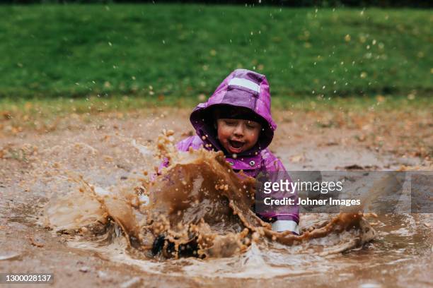 toddler girl splashing in puddle - västra götalands län stockfoto's en -beelden