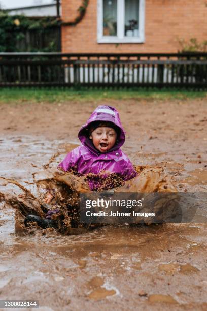 toddler girl splashing in puddle - kids mud stock pictures, royalty-free photos & images