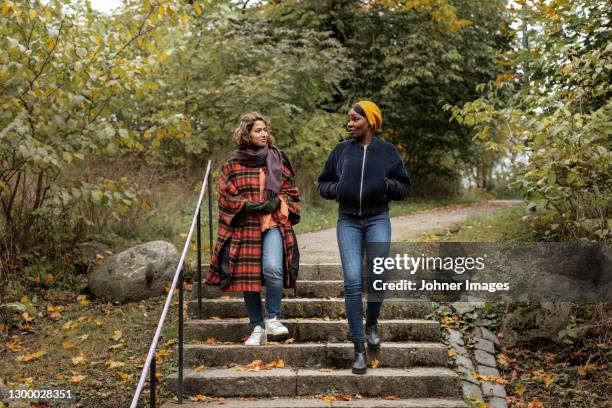 two young women walking in park - two people talking outside stock pictures, royalty-free photos & images