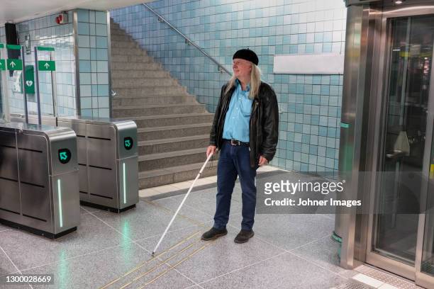 man with white cane standing at metro station - blind man stockfoto's en -beelden