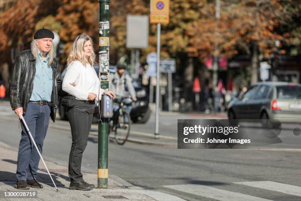 senior couple standing at zebra crossing - zebra crossing stock-fotos und bilder