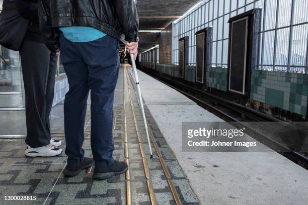 man with white cane standing at train station - blind man stock pictures, royalty-free photos & images