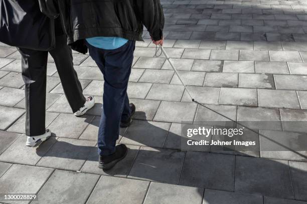 couple with white cane walking in street - blind persons cane stock pictures, royalty-free photos & images