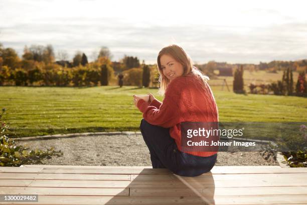 young woman sitting on porch and drinking coffee - back porch stockfoto's en -beelden