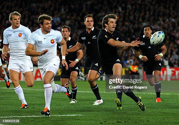 Centre Conrad Smith of the All Blacks passes the ball as the French defence closes induring the 2011 IRB Rugby World Cup Final match between France...