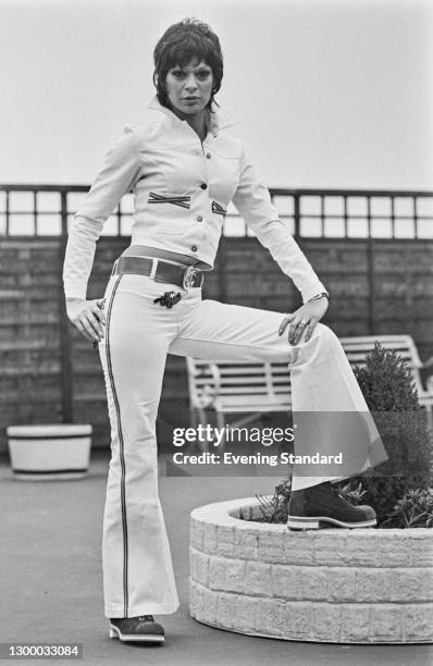 Model wearing a flared trouser suit with the Disney cartoon dog Pluto and a belt with an anchor motif, UK, 1st March 1972.