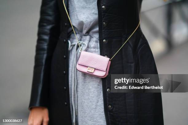 Natalia Verza aka Mascarada wears a black leather long coat with shoulder pads from Fendi, a gray t-shirt, gray sport jogger pants, a pink Fendi mini...