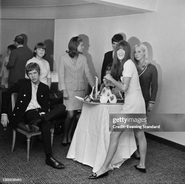 British television presenter Cathy McGowan cuts into a cake at a party with singer Scott Walker of the Walker Brothers, UK, September 1966.