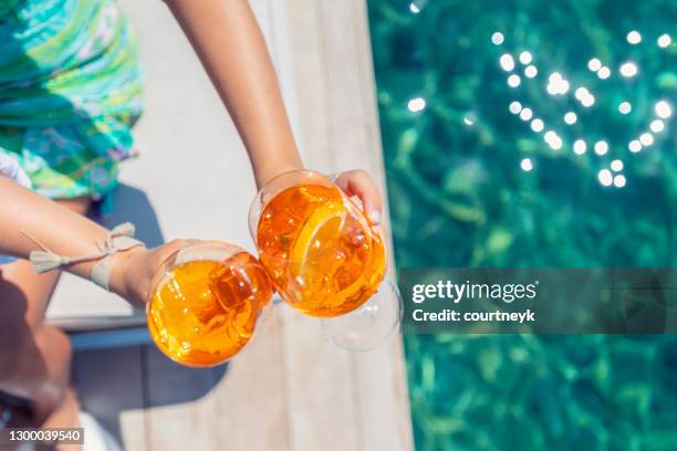 women  toasting with a spritz cocktail on a deck over the ocean. - beach cocktail party stock pictures, royalty-free photos & images