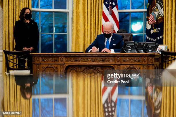 President Joe Biden signs several executive orders directing immigration actions for his administration as Vice President Kamala Harris looks on in...