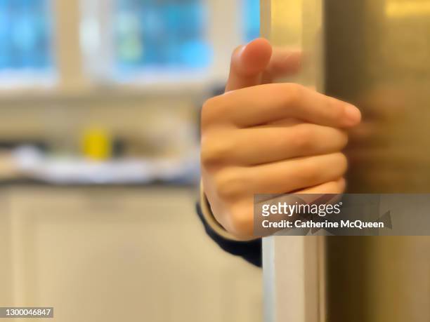 unrecognizable mixed-race teen girl reaches for food from the refrigerator - refrigerator door stock pictures, royalty-free photos & images