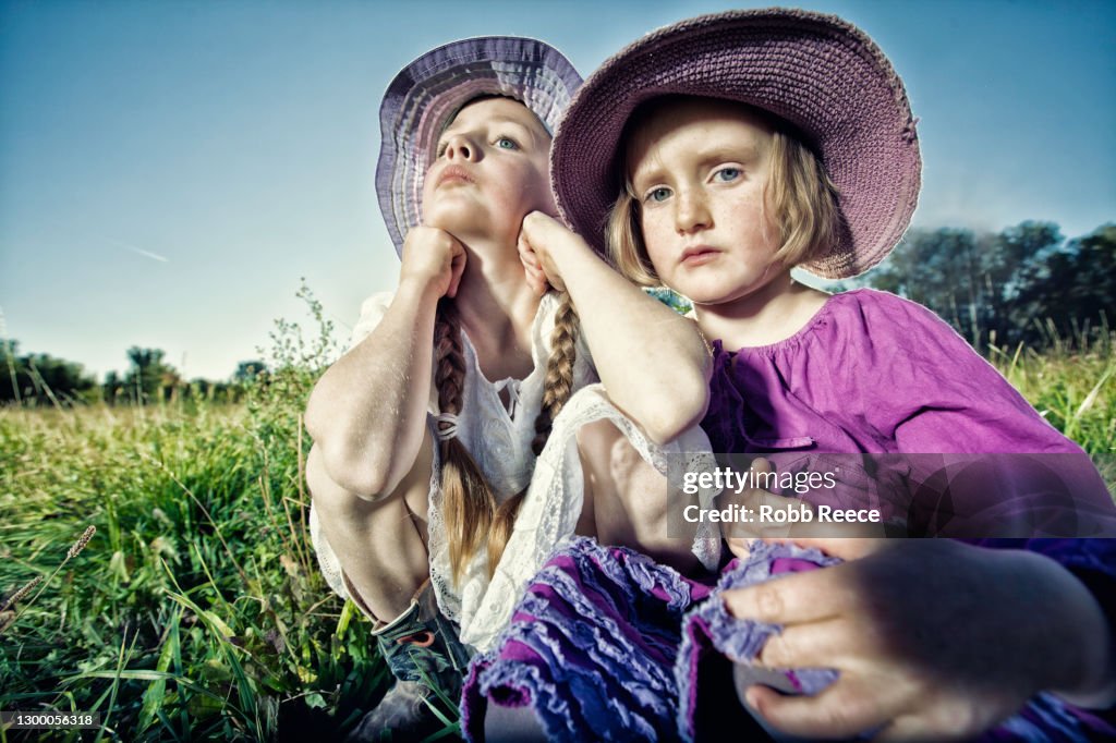 Two Young Girls Sitting In A Field