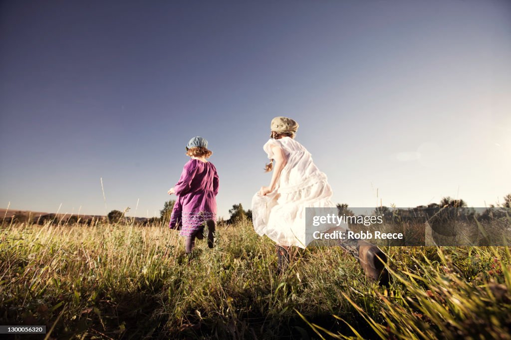 Two Young Girls Running In A Field