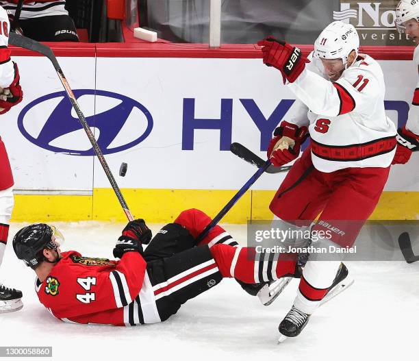 Jordan Staal of the Carolina Hurricanes knocks the puck from in between the legs of Calvin de Haan of the Chicago Blackhawks at the United Center on...