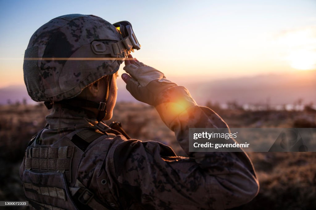 Female Army Solider Saluting against sunset sky