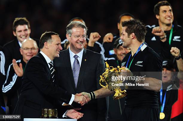 Prime Minister of New Zealand Hon John Key shakes hands with captain Richie McCaw of the All Blacks as he holds the Webb Ellis Cup after an 8-7...