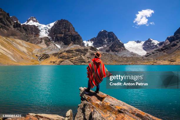 traveler in a poncho on the background of condoriri peak and lake in cordillera real, andes, bolivia - bolivia fotografías e imágenes de stock