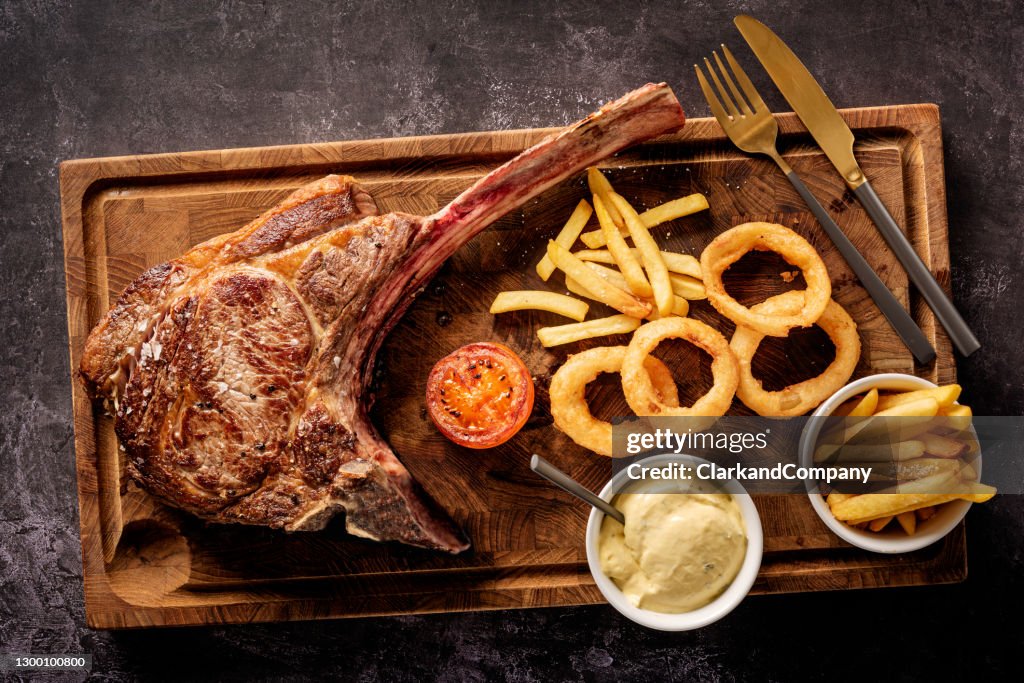 Tomahawk Steak mit Fries Zwiebelringen und Bearnaise Sauce.