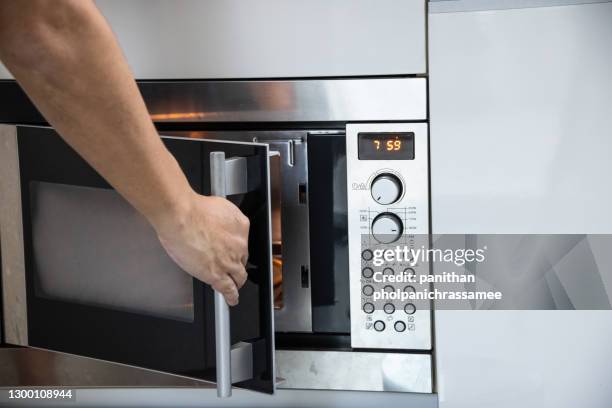 close up hand open microwave oven. - mikrowelle stock-fotos und bilder