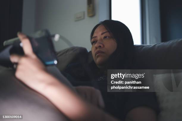 asian woman on sofa use mobile in the dark room. - glow in the dark monster models stockfoto's en -beelden