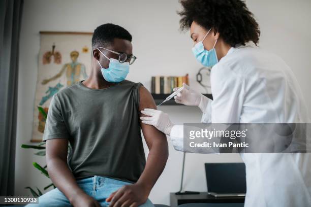 young african american man taking covid 19 vaccine - covid 19 vaccine stock pictures, royalty-free photos & images