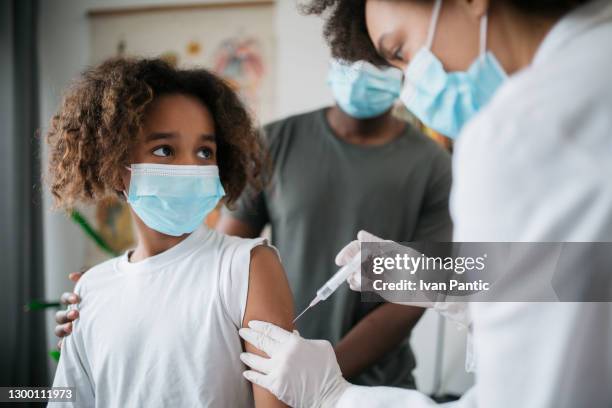 close up of a young african american little girl taking a covid 19 vaccine - safe injecting stock pictures, royalty-free photos & images