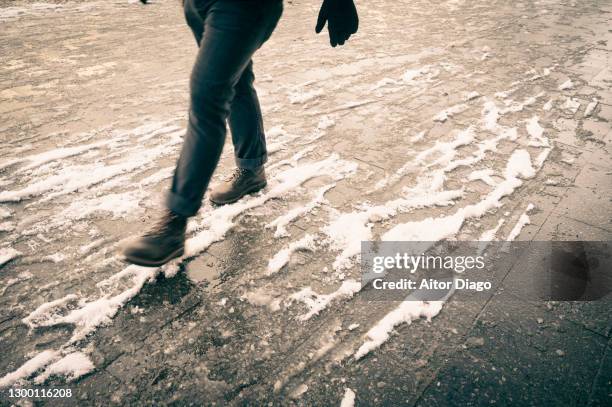 unrecognizable person walking down the street in a snowy day. berlin, germany. - slippery stock-fotos und bilder