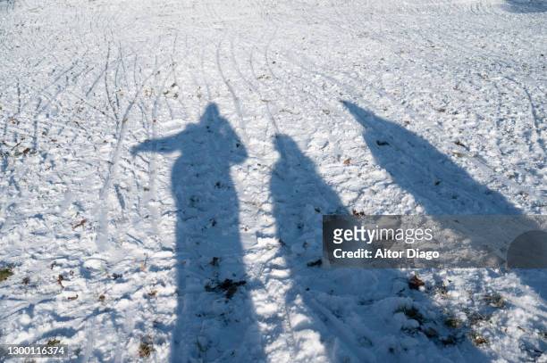 shadow of three people cast on snow in winter. - frostbite fingers stock-fotos und bilder