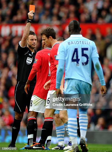 Referee Mark Clattenburg shows a red card to Jonny Evans of Manchester United during the Barclays Premier League match between Manchester United and...