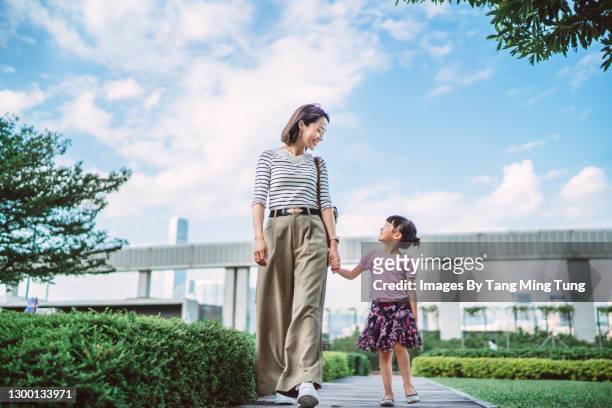 mom & daughter strolling in park joyfully - family weekend activities stock pictures, royalty-free photos & images