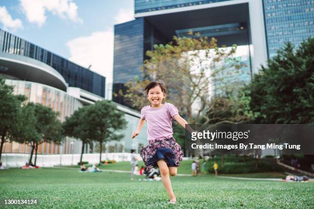 lovely little girl running in park joyfully - city life authentic stock pictures, royalty-free photos & images