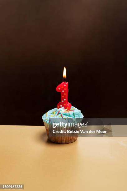studio shot of cupcake with a number one candle burning. - birthday candle number stock pictures, royalty-free photos & images