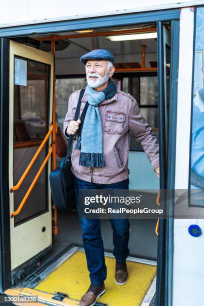 senior business man using public transportation - bus . reifer geschäftsmann holt an einem kalten wintertag einen stadtbus - fahrzeugtür stock-fotos und bilder