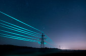 Electricity transmission towers with glowing wires against the starry sky.