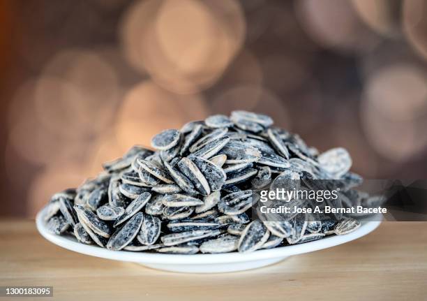 plate of sunflower seeds in shell and salt on a multicolored background. - sonnenblumenkerne stock-fotos und bilder