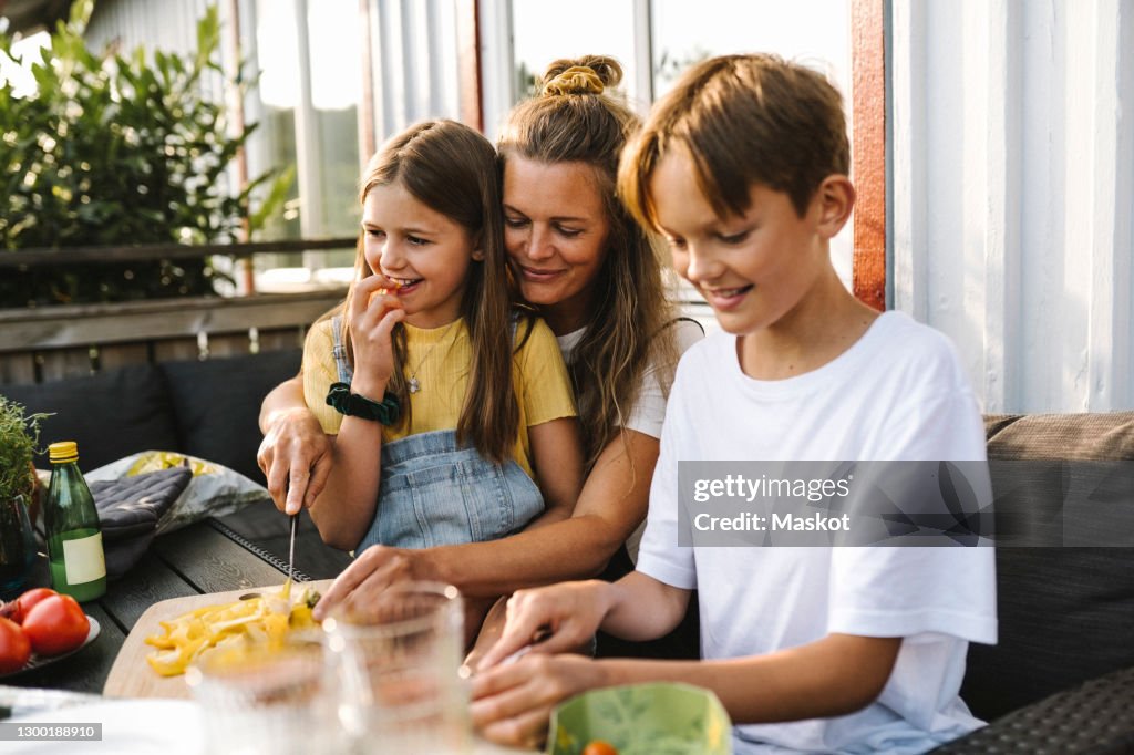 Smiling mother cutting vegetable on table in balcony
