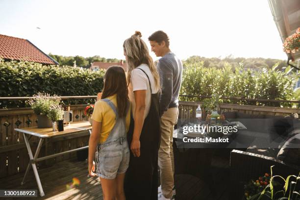 mother and father with daughter standing in balcony - couple balcony stock-fotos und bilder