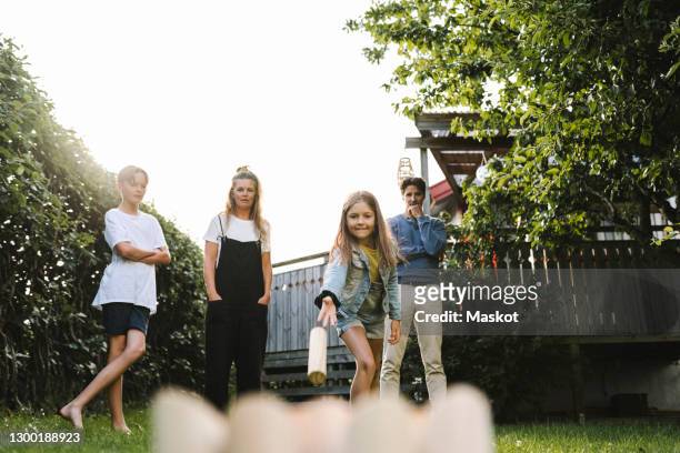 girl playing molkky with family in back yard - backyard games stockfoto's en -beelden