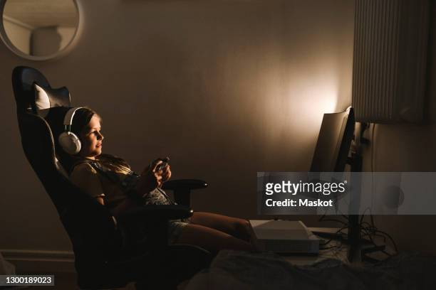 pre-adolescent girl playing video game over television at home - pre game stockfoto's en -beelden
