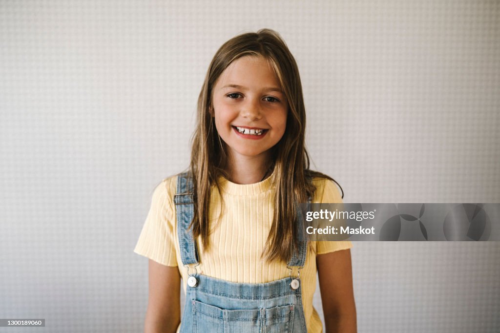 Smiling girl against white wall at home