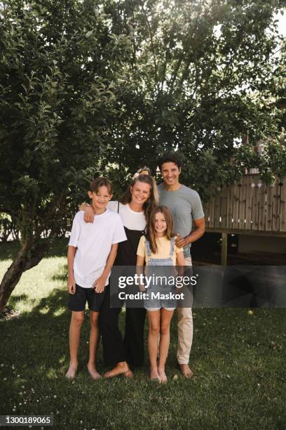 happy family standing against tree in back yard - family portrait stockfoto's en -beelden