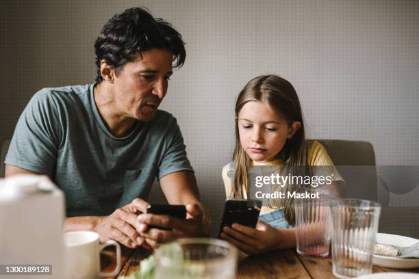 daughter and father using smart phone over dining table at home - smart phone on table stock pictures, royalty-free photos & images