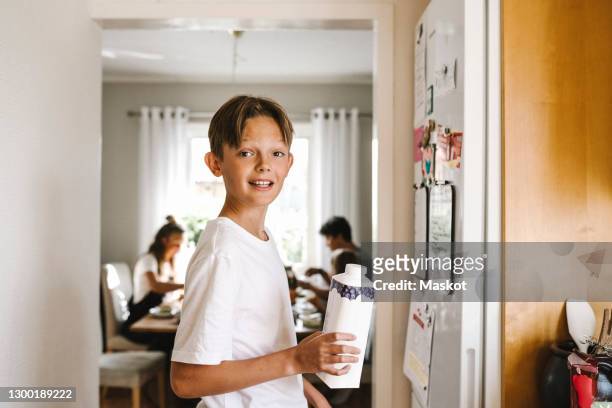 boy with juice pack standing in kitchen - juice carton 個照片及圖片檔