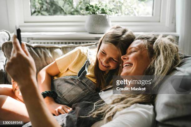 smiling mother and daughter using digital tablet in living room - ten stock-fotos und bilder