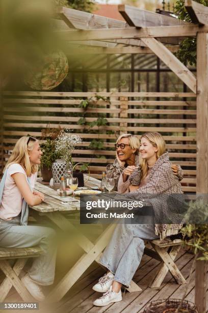 female friends spending time with grandmother at table in back yard - family back yard stockfoto's en -beelden