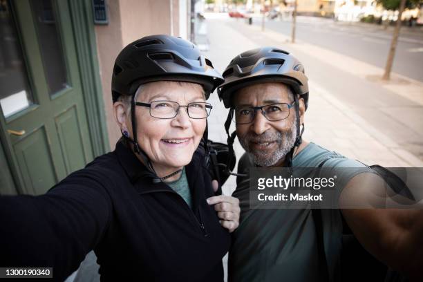 happy couple taking selfie outside house - sports helmet photos et images de collection