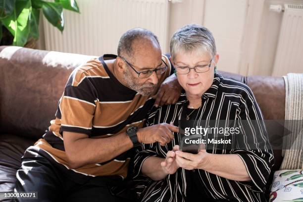 senior couple using smart phone in living room - blank room stockfoto's en -beelden