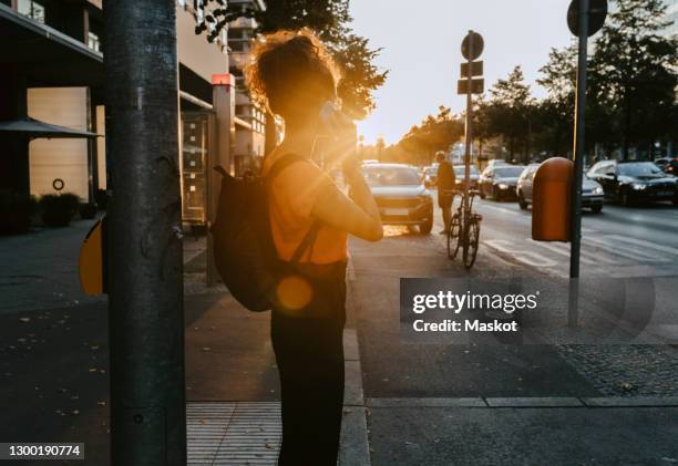 businesswoman talking over smart phone while standing on footpath in city - career path stock pictures, royalty-free photos & images