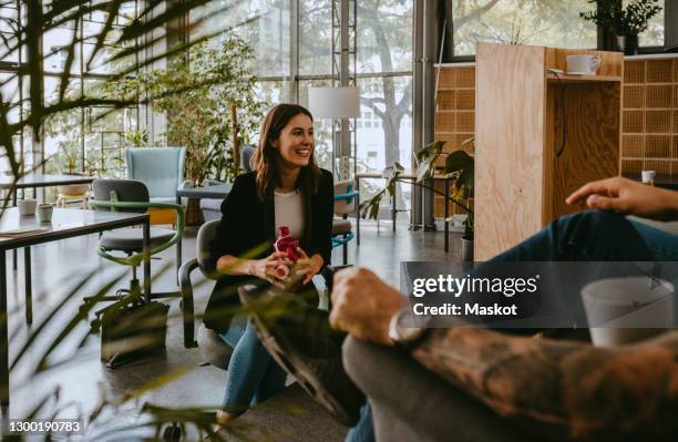 smiling female entrepreneur discussing with male colleague during coffee break at coworking office - business meeting coffee stock pictures, royalty-free photos & images