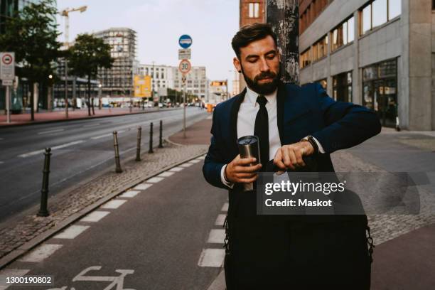 male entrepreneur checking time while standing on footpath - keine zeit stock-fotos und bilder